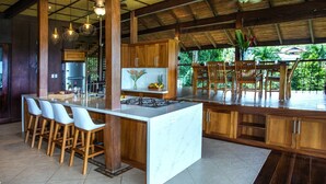 A modern kitchen with a central island, bar stools, and wooden cabinetry.