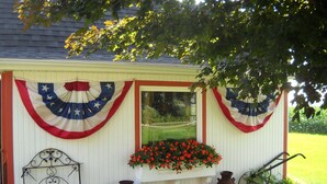 A small, white structure with decorative American flags and a flower box.