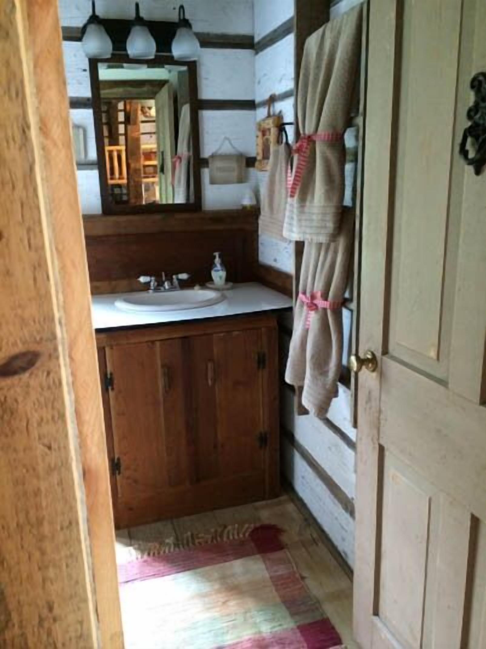 Ein Badezimmer mit Holzsärchen, einem Waschbecken, einem Spiegel und einem Handtuch an der Wand.