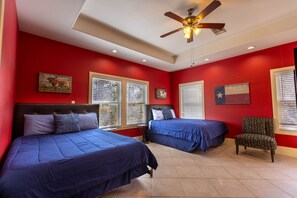 A room with two beds, a ceiling fan, and a Texas flag on the wall.