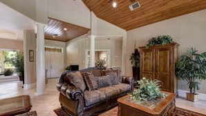 A spacious living room with a high ceiling, a large wooden cabinet, and a leather sofa.