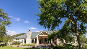 A stone house with a covered porch, a chimney, and a lawn.