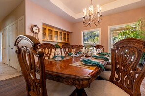 A dining room with a wooden table, chairs, and a chandelier.