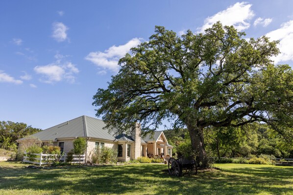A two-story stone house with a large tree in the front yard.