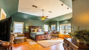 A bedroom with a bed, a dresser, a chair, a desk, and a ceiling fan.