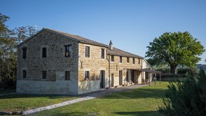 Un edificio in pietra su due piani con un portico coperto e un piccolo giardino.