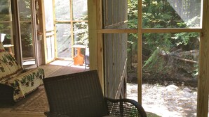 Eine Holterrasse mit einem Korbstuhl und einem Glastisch.