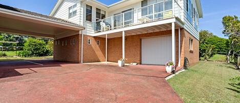 Ett tvåvåningshus med en överbyggd uppfart, ett garage och en stor gräsmatta framför huset.