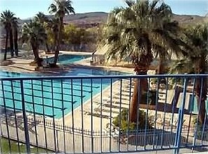 A swimming pool surrounded by palm trees and a fence.