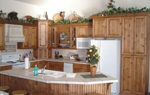 A kitchen with wooden cabinets, a central island, a microwave, and a refrigerator.