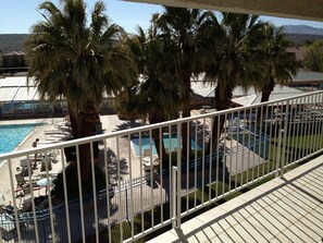 A pool area with palm trees, lounge chairs, and a fenced deck.
