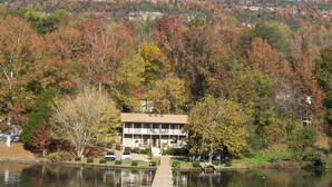Un bâtiment situé au bord d’un lac, doté d’un quai, entouré d’un feuillage automnal et avec une colline en arrière-plan.