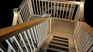 Una escalera de madera con barandillas y pasamanos blancos, que conduce a un nivel superior.