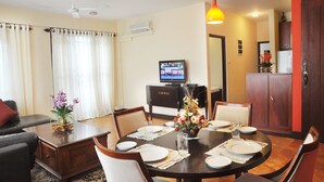 A dining area with a round table set for four, a television on a cabinet, and a ceiling fan. - Peaceful Harmonious Condo Equipped Kitchen Two Bath Three Bedrooms Aircondition (Mount Lavinia)