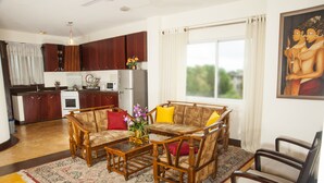 A living room with a sofa set, coffee table, and a dining area with a refrigerator and microwave. - Peaceful Harmonious Condo Equipped Kitchen Two Bath Three Bedrooms Aircondition (Mount Lavinia)