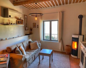 Una sala de estar acogedora con sofá, mesa, chimenea y ventana con cortinas.