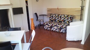 A dining area with a white table and chairs, a sofa with a colorful polka dot pattern, and a small round table. - Best location in Bologna. Studio equipped for long stays. SuperHost since 2011. (Bologna)