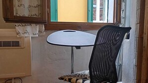 A small room with a single table and chair, a window with a view of a yellow building, and a door with a handle. - Best location in Bologna. Studio equipped for long stays. SuperHost since 2011. (Bologna)