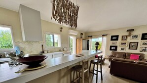 Een moderne keuken met een groot eiland, barkrukken en een eethoek met een bruine leren bank.
