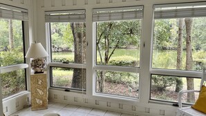 A room with large windows, a lamp, a chair, and a decorative shell piece.