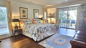 Une chambre dotée d’un grand lit, d’un coin salon avec un canapé, d’une table à manger et offrant une vue sur l’extérieur.