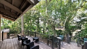 Une terrasse en bois, agréée de mobilier d’extérieur, entourée d’arbres et offrant une vue sur un quartier résidentiel.