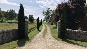 A gravel path leading through a stone gate into a grassy area with trees.