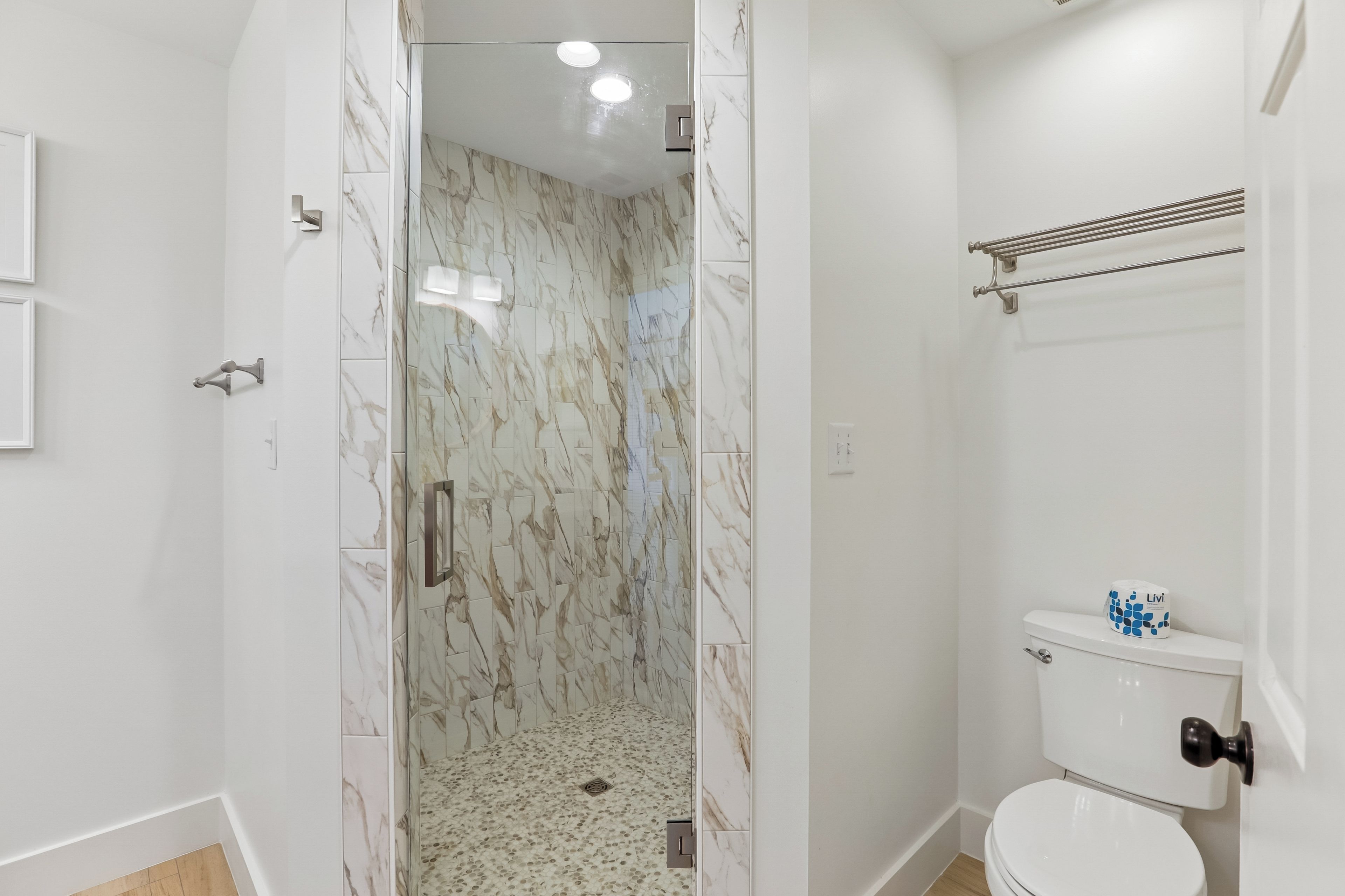 A bathroom with a shower, toilet, and a towel rack.
