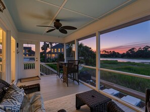 A covered porch with a ceiling fan, a dining table, and chairs. There is a view of a body of water and greenery. - Spacious 4Br w/ Incredible Views from Deck! (Hilton Head Island)