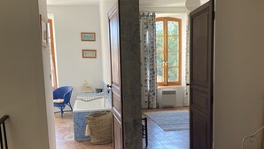 Um corredor que dá para uma sala de jantar com uma cadeira azul, uma mesa e um mapa na parede.