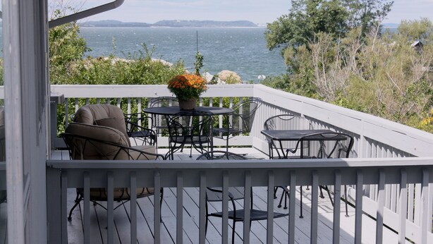 A wooden deck with outdoor furniture, a potted plant, and a view of the sea. - Beautiful Oceanfront Home in Estate Setting Gloucester — FALL RENTAL AVAILABLE! (Gloucester)
