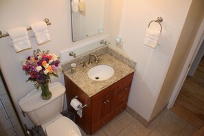 Een badkamer met toilet, wastafel, opbergruimte en een spiegel.