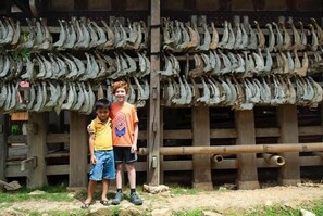 A rustic wooden structure with multiple rows of dried fish displayed on racks. - Mama Tia Family Homestay (Rinding Batu)