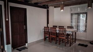 Un coin repas avec une table et des chaises en bois, une porte et une fenêtre avec un rideau.