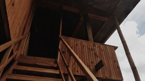 Un escalier en bois menant à un balcon orné d’un motif en treillis.