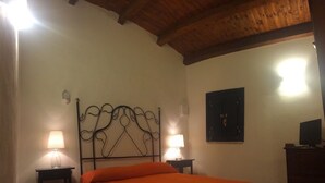 A bedroom with a bed, two bedside lamps, a wooden ceiling, and a wall-mounted TV. - COUNTRY HOUSE IMMERSED IN A LEMONET 2 km from the sea and Noto - Wifi - climate (noto)