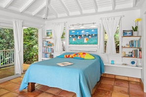 A bedroom with a bed, a window with a view of greenery, a bookshelf, and a painting.
