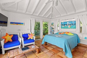 A room with a bed, two chairs, a table, and a TV.