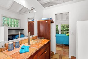 Un bagno con un lavandino in vetro, mobili in legno, uno specchio e una finestra vista verde.