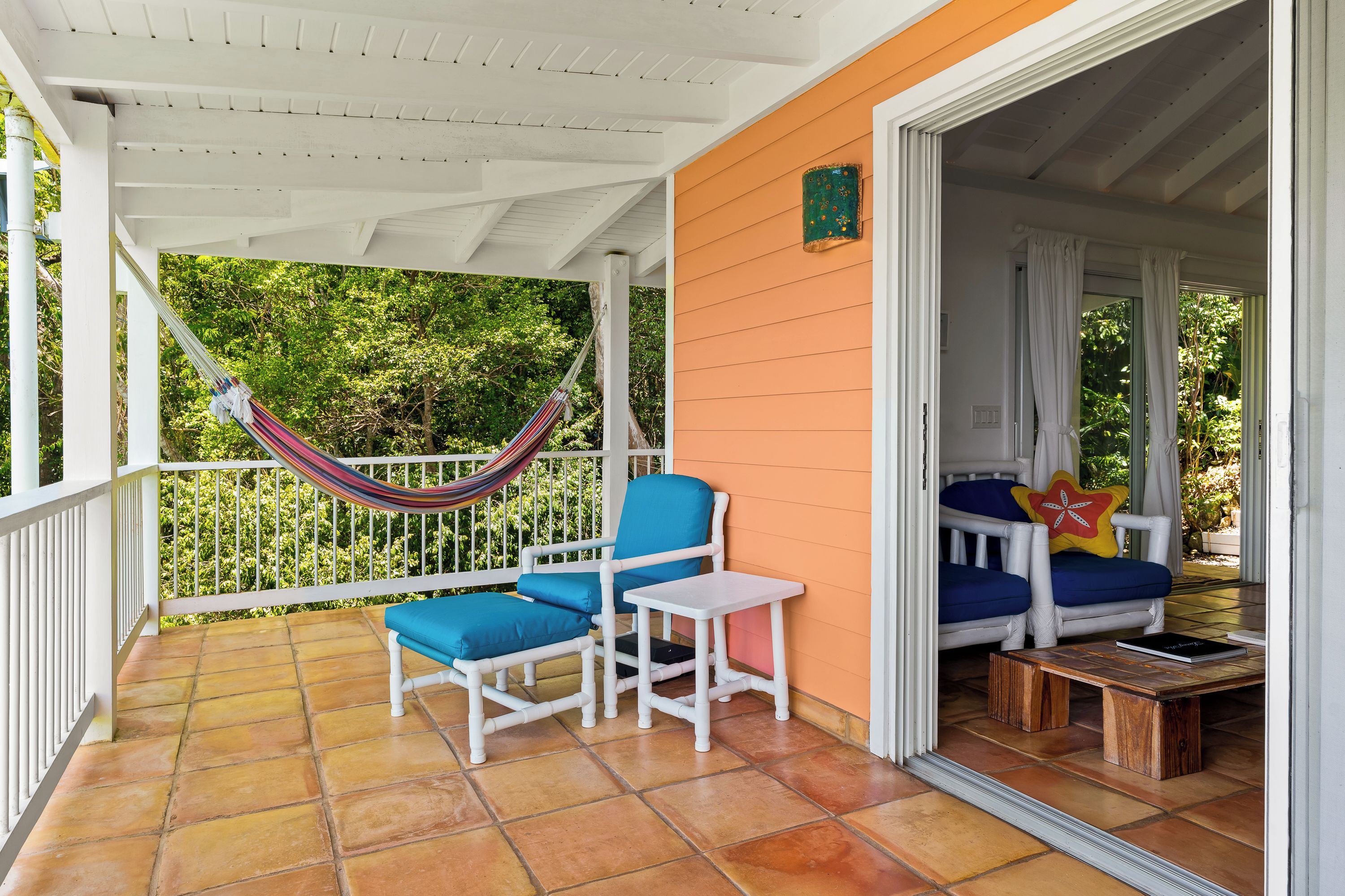 Un espace extérieur abrité, aménagé avec un hamac, deux chaises et une petite table.