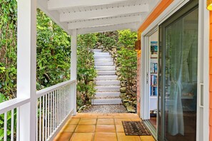 A covered outdoor staircase leading to a door, surrounded by greenery and a stone wall. - Sea Cottage - Charming and Romantic with a Stunning View (St. John)
