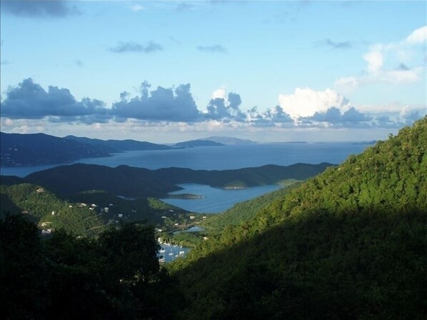 A coastal landscape with a lake, hills, and a small settlement with buildings near the water.