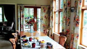 Un coin repas avec une table en bois, des chaises et un vase de fleurs.