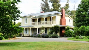 A two-story house with a balcony, surrounded by lush greenery. - Historic Hawkesbury Homestead Estate, Swimming Pool, Tennis court, Wine Country. (Blenheim)