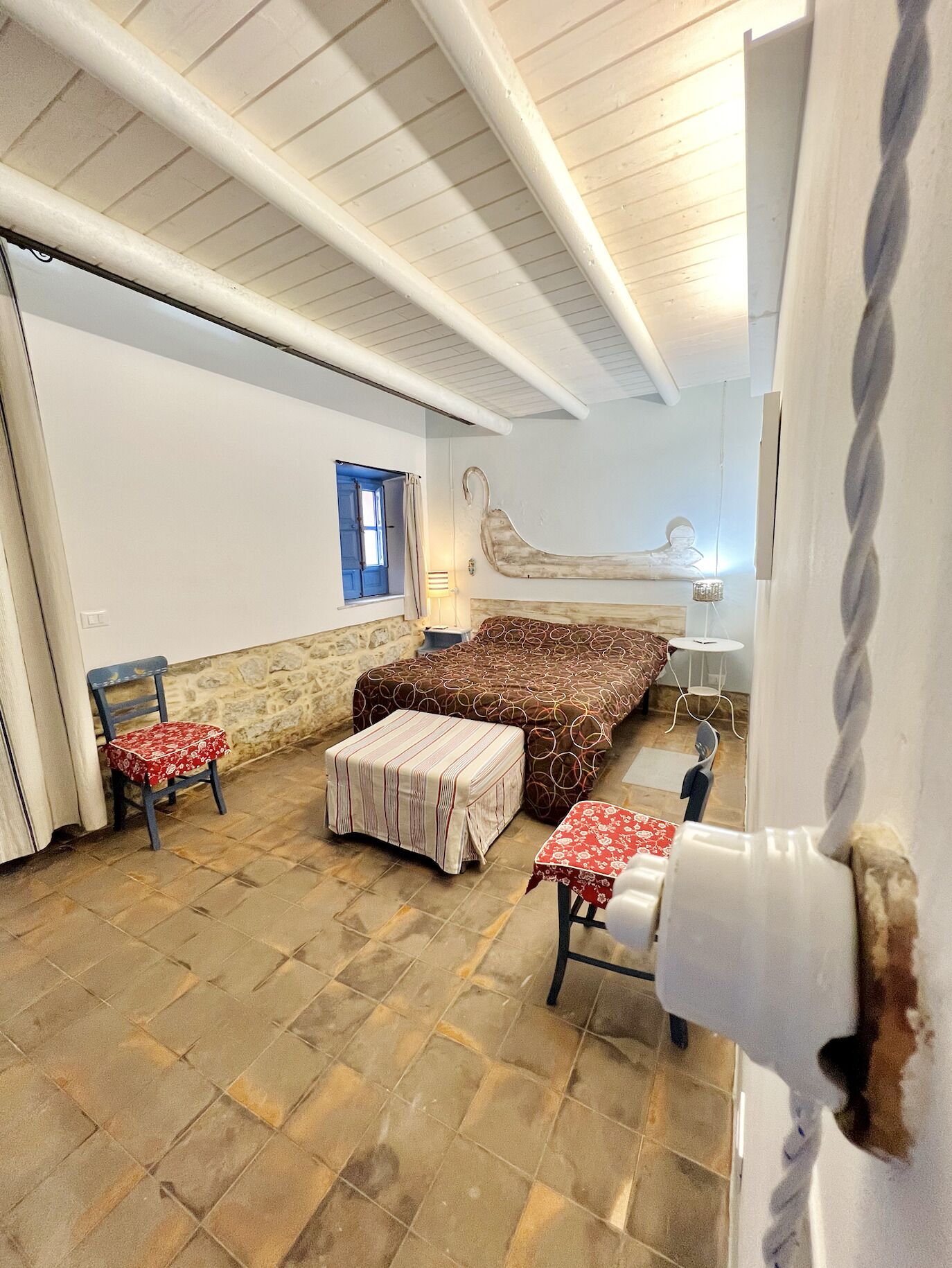 A room with a bed, a chair, a small table, and a window.