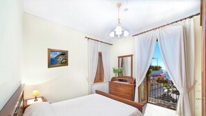 Una camera d'albergo con un letto, una cassettiera, un comodino con una lampada, un quadro, un balcone con vista e un cartello che indica Wi-Fi gratuito.