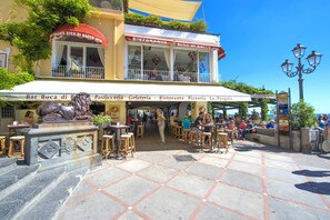 A restaurant with outdoor seating, a statue, and a tiled pavement. - Villa Costanzo - Beach Front - Air Conditioned and Free Wi- Fi (Positano)