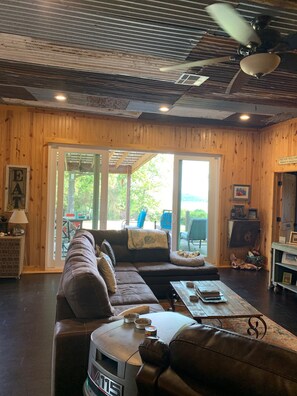 A cozy living room with a sectional sofa, a coffee table, and a ceiling fan.