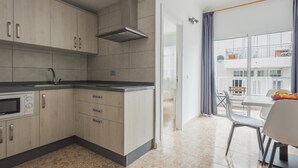 A modern kitchen with light wood cabinets, a stainless steel range hood, and a built-in oven.