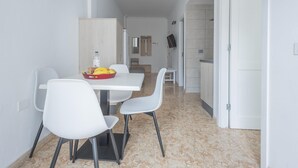 A modern kitchen with white cabinets, a dining table with chairs, and a fruit bowl on the table.